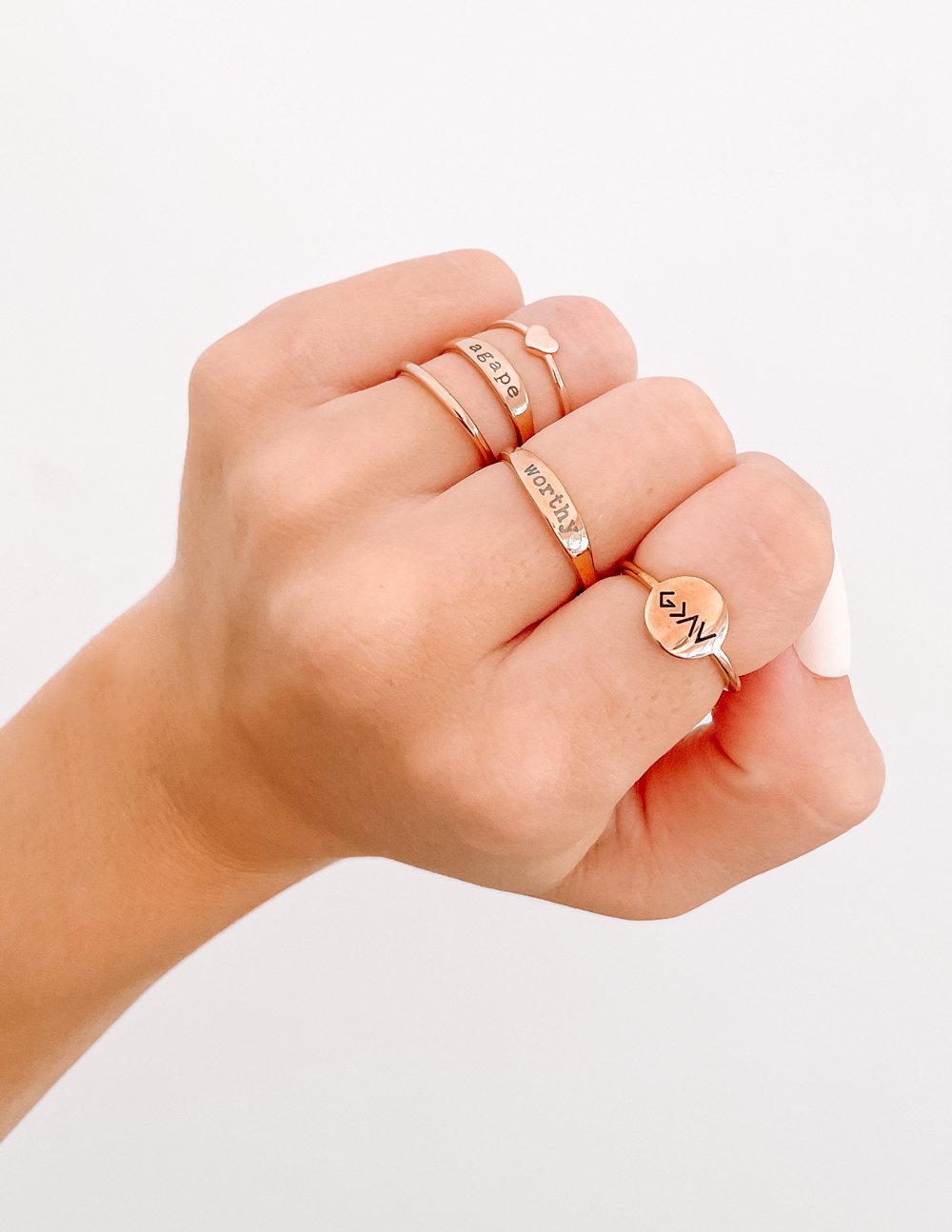 Worthy ring styled with additional rings on a hand against a light background