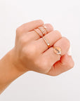 Worthy ring styled with additional rings on a hand against a light background